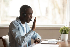 Black guy wear headset start lesson online look at laptop screen wave hand greeting tutor improves foreign language knowledge get skills through internet, education distantly using modern tech concept